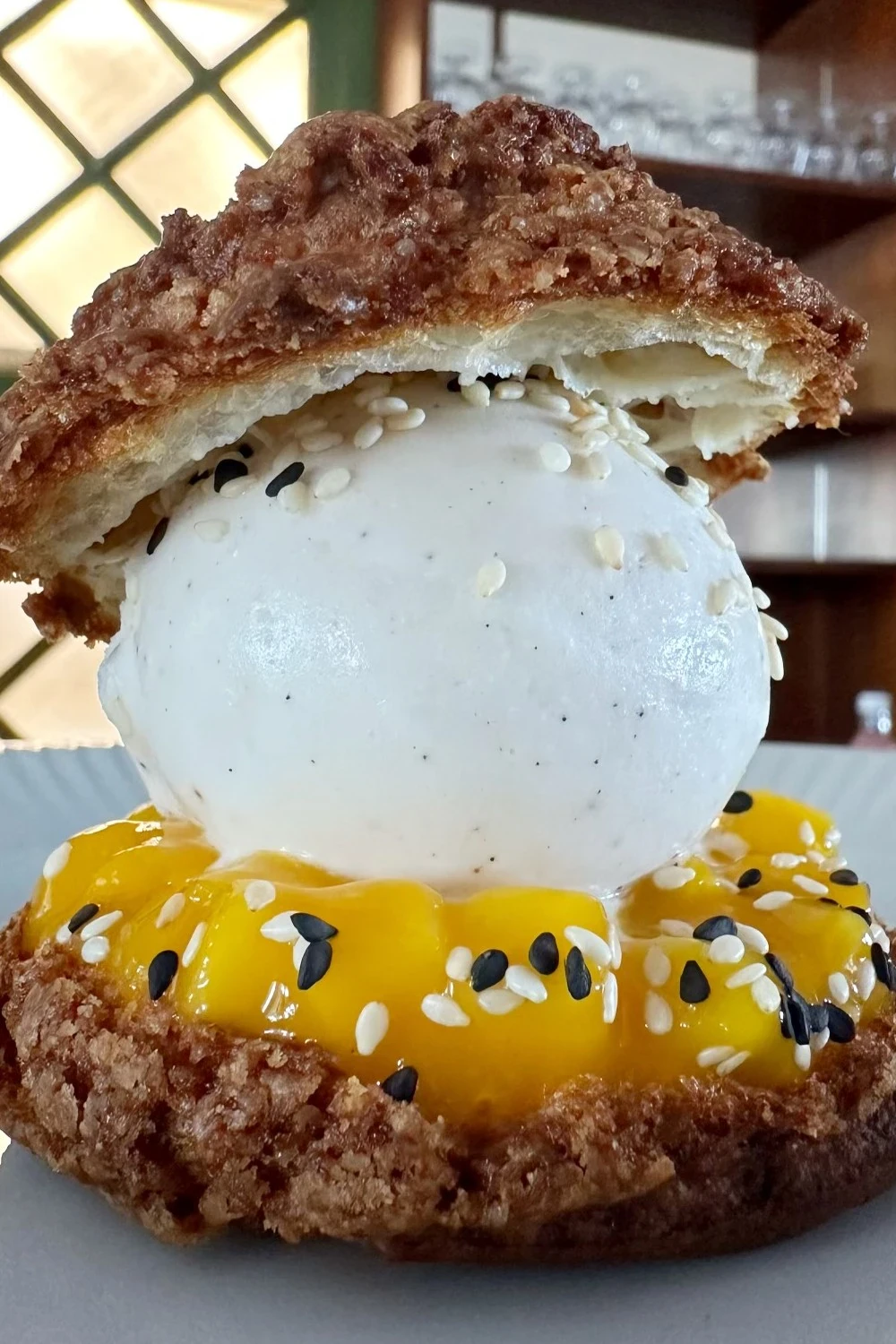 Choux au craquelin med mangokompot, ristet sesam og vaniljeis. Serveres med lun chokoladesauce