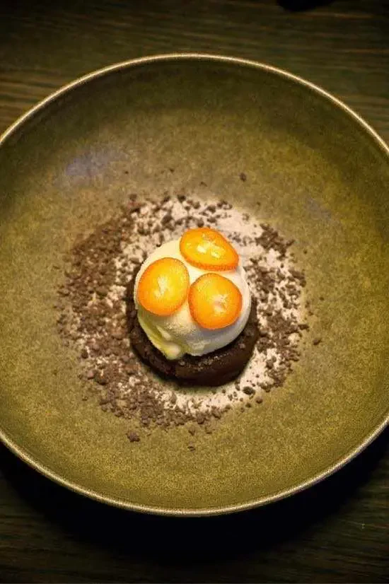 Appelsinsorbet på bund af mørk chokolademousse, råmarinerede kumquats, med drys af brunkage og krystalliseret mørk chokolade.