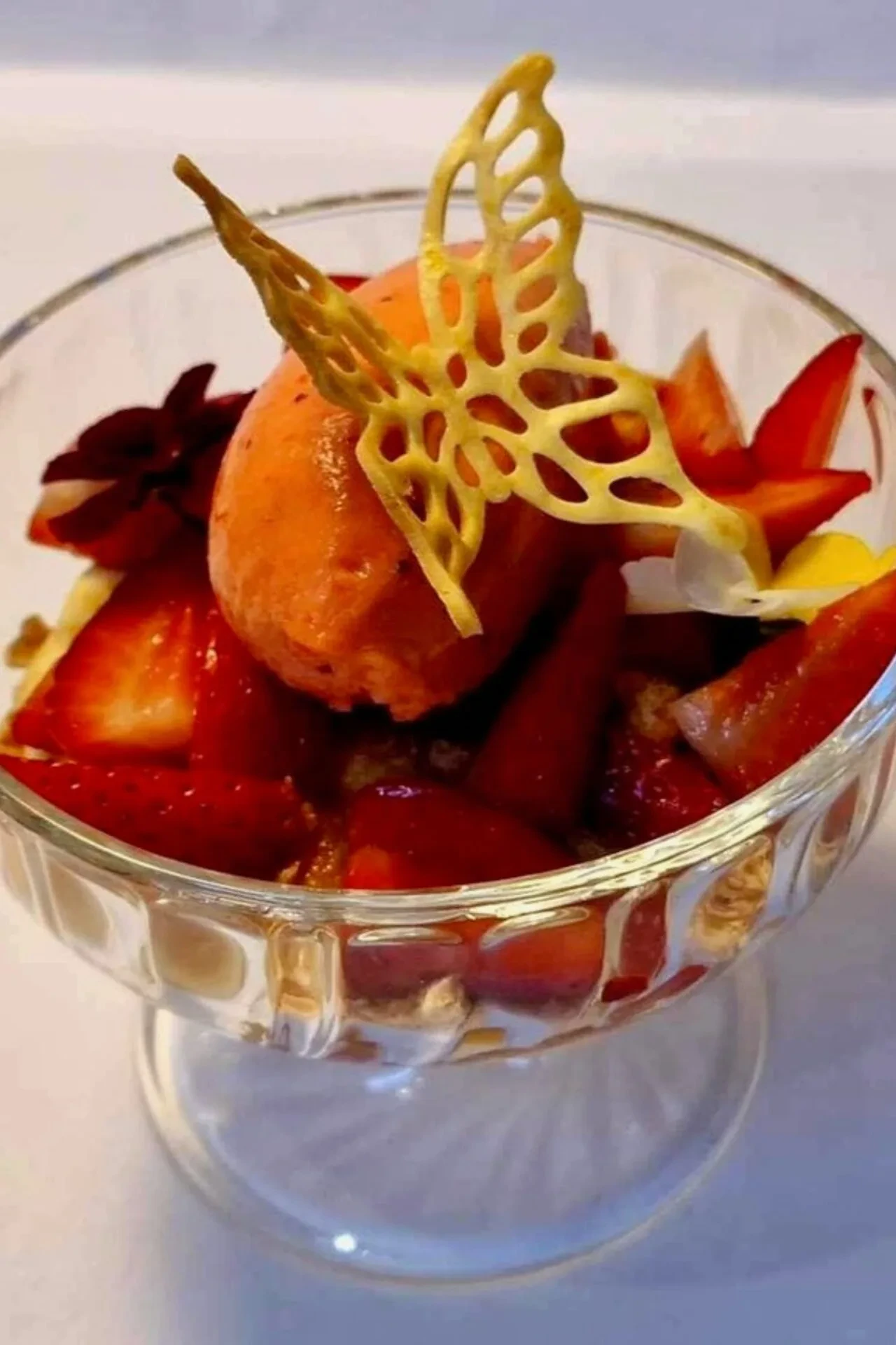 Jordbær Romanoff med jordbær marineret i appelsin sukker og cointreau, vanilje creme, makroner og jordbær sorbet, afsluttet med en appelsin tuille